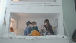 Trois enfants en train de se faire lire une histoire dans leur lit par leur maman.