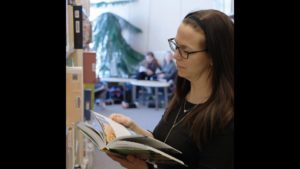 Pascale Grenier tient un livre dans une bibliothèque