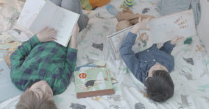 Deux enfants qui lisent dans un lit.