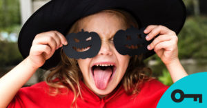 jeune fille déguisée en sorcière avec des citrouilles noires en papier devant les yeux