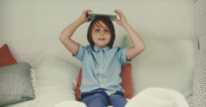 Un enfant qui tient un livre sur sa tête dans un lit.