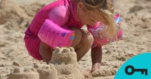 Une fillette agenouillée dans le sable en train de construire un château de sable