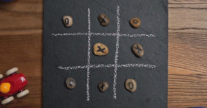 Un jeu de tic-tac-toe fait avec une ardoise et des roches