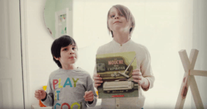 2 enfants tiennent le livre de l'Heure du conte : La mouche dans l'aspirateur.