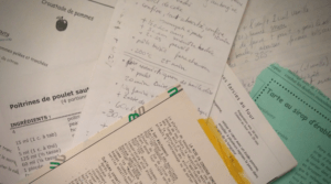 Une pile de recettes sur papier, certaines manuscrites, d'autres imprimées.