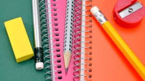 Des cahiers spiralés colorés, une efface, un aiguisoir et des crayons de plomb.