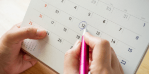 Une main qui encercle une date sur un calendrier.