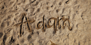 Le nom Adam écrit dans le sable.
