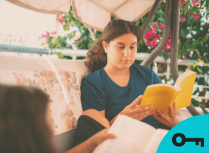 Une fille lit un livre dans une chaise extérieure près de sa soeur.