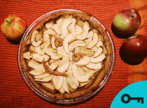 Une tarte décorée d'un sourire avec des pommes à côté.