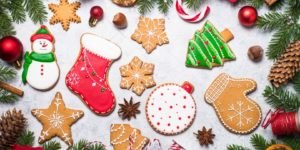 Des biscuits décorés, des pommes de pin, des branches de sapins, des étoiles d'anis, des rondelles d'orange séchée et des boules de Noël rouges.