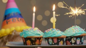 Petits gâteaux décorés avec du glaçage, des chandelles et un feu de bengal pour célébrer un anniversaire
