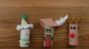 Un lutin, une maison et un renne qui sont fabriqués avec des rouleaux de papier de toilette pour fabriquer un joli village d'hiver