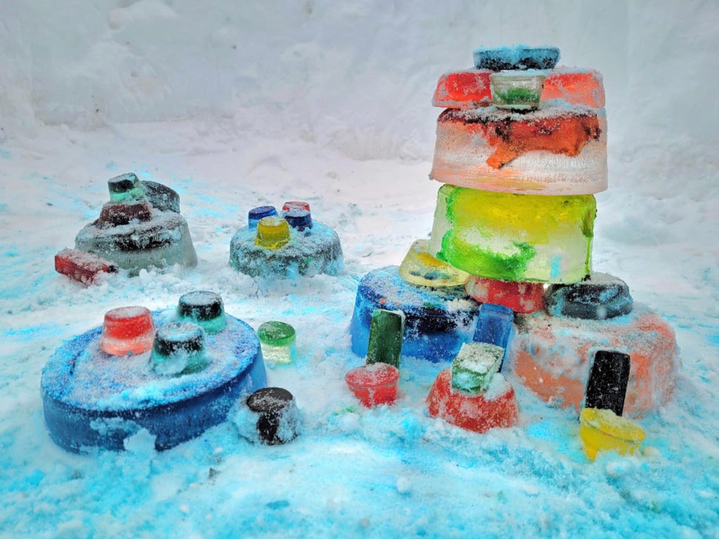 Sculptures de glace faites de blocs colorés empilés sur la neige par des enfants