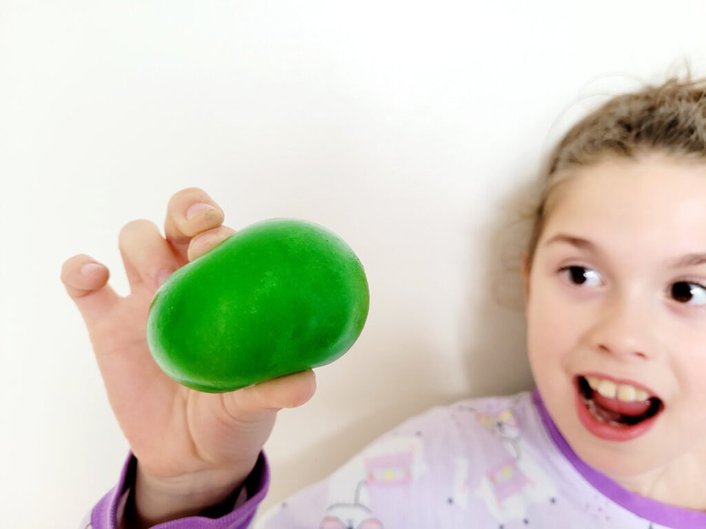 Un enfant montrant le résultat de l'expoérience de science: un oeuf mou coloré en vert